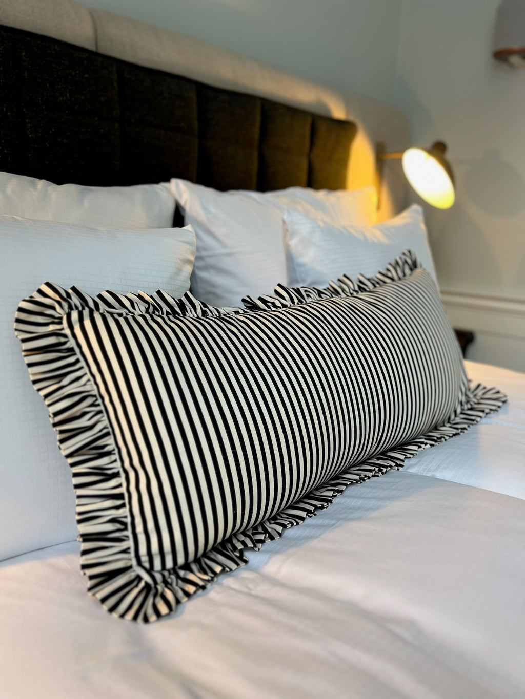Black and white striped ruffle pillow on a bed villa copenhagen