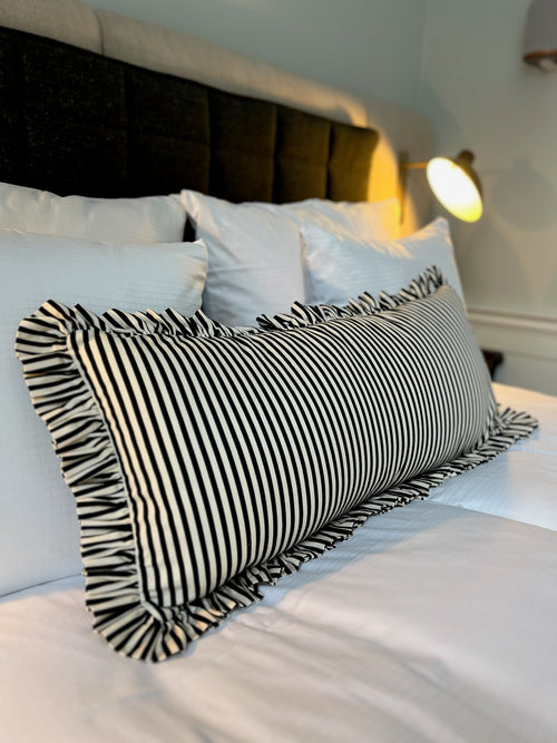 Black and white striped ruffle pillow on a bed villa copenhagen