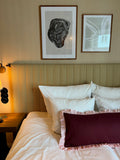 Bedroom with a bed featuring pillows and a headboard, with two framed artworks on the wall.