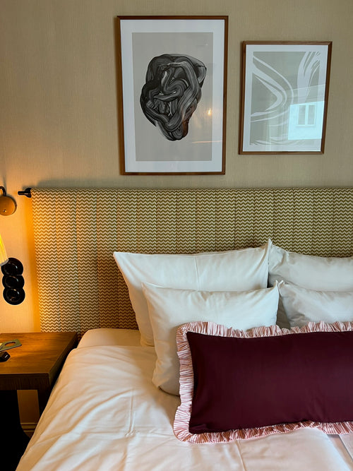 Bedroom with a bed featuring pillows and a headboard, with two framed artworks on the wall.